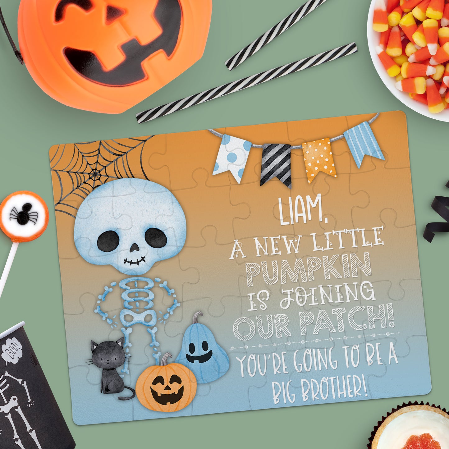 A jigsaw puzzle with a skeleton, black cat, pumpkins, and festive banner reads: "Liam, a new little pumpkin is joining our patch! Youâre going to be a big brother!.