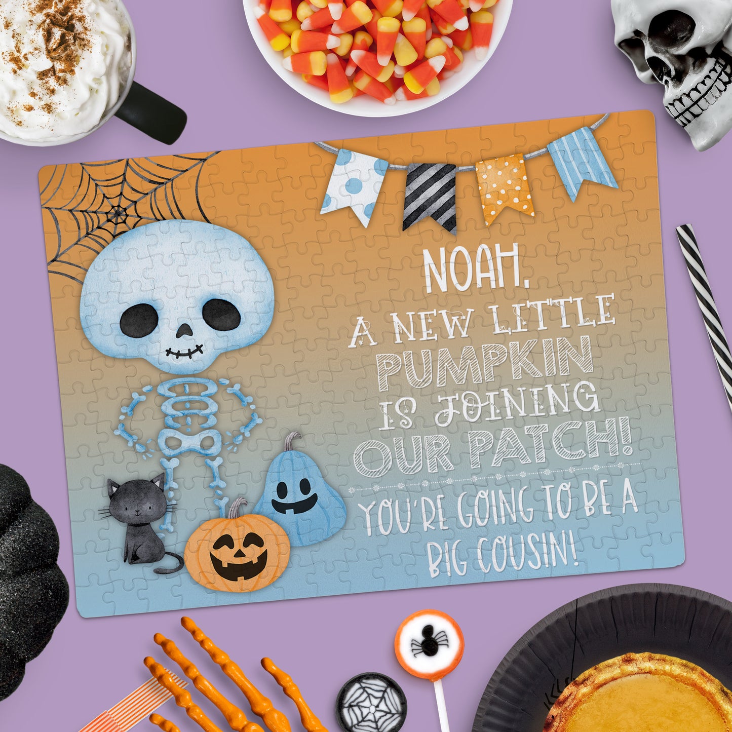 A Halloween-themed puzzle with a skeleton, cat, pumpkin, and spider web, announcing, "Noah, a new little pumpkin is joining our patch! You're going to be a big cousin!.