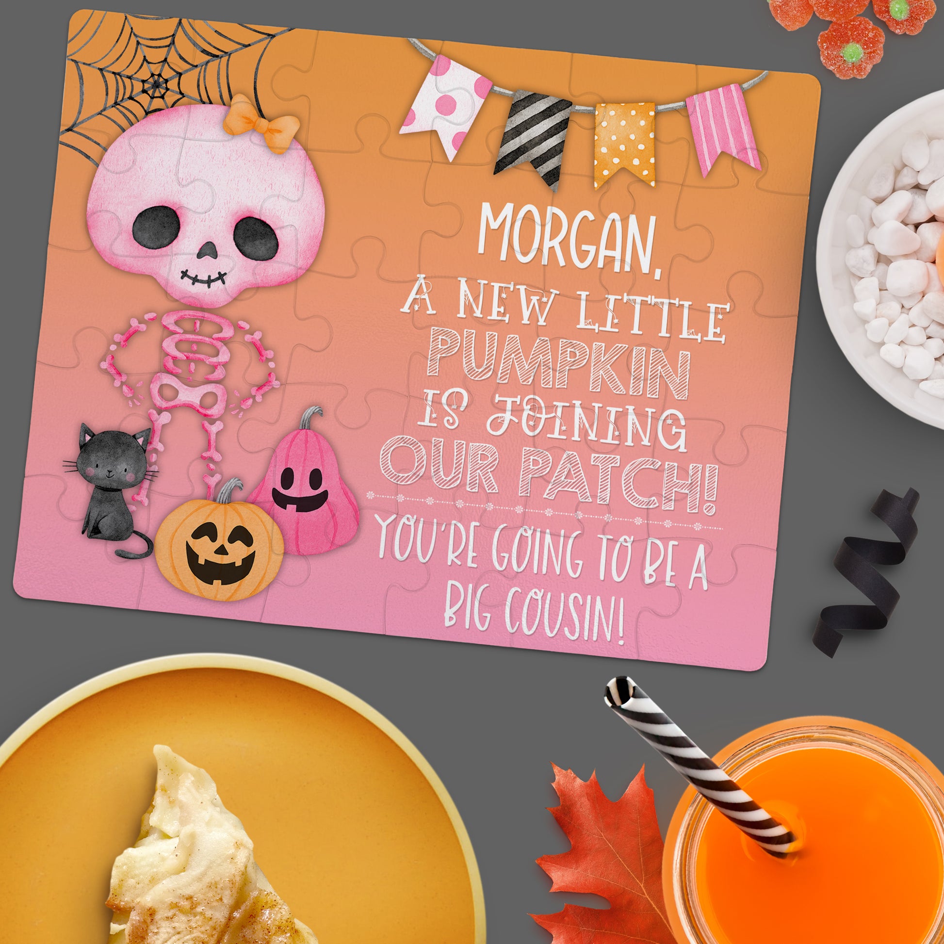 A jigsaw puzzle on a table announces "Morgan, a new little pumpkin is joining our patch! You're going to be a big cousin!" with Halloween-themed illustrations.