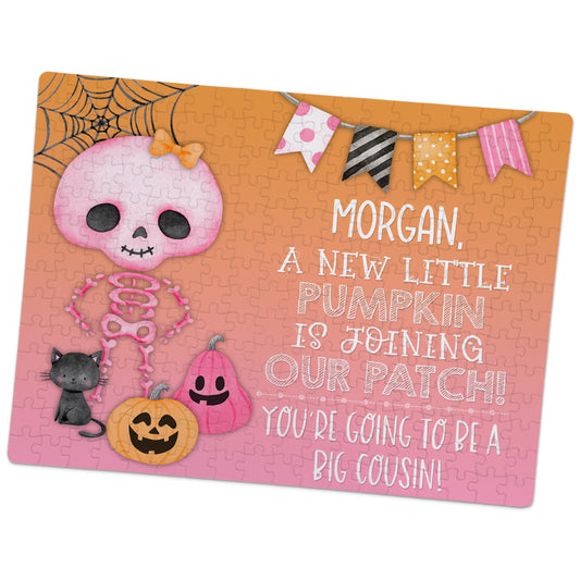 A Halloween-themed jigsaw puzzle announces a new baby joining the family, with a pink skeleton, pumpkins, a cat, and a message that Morgan will be a big cousin.