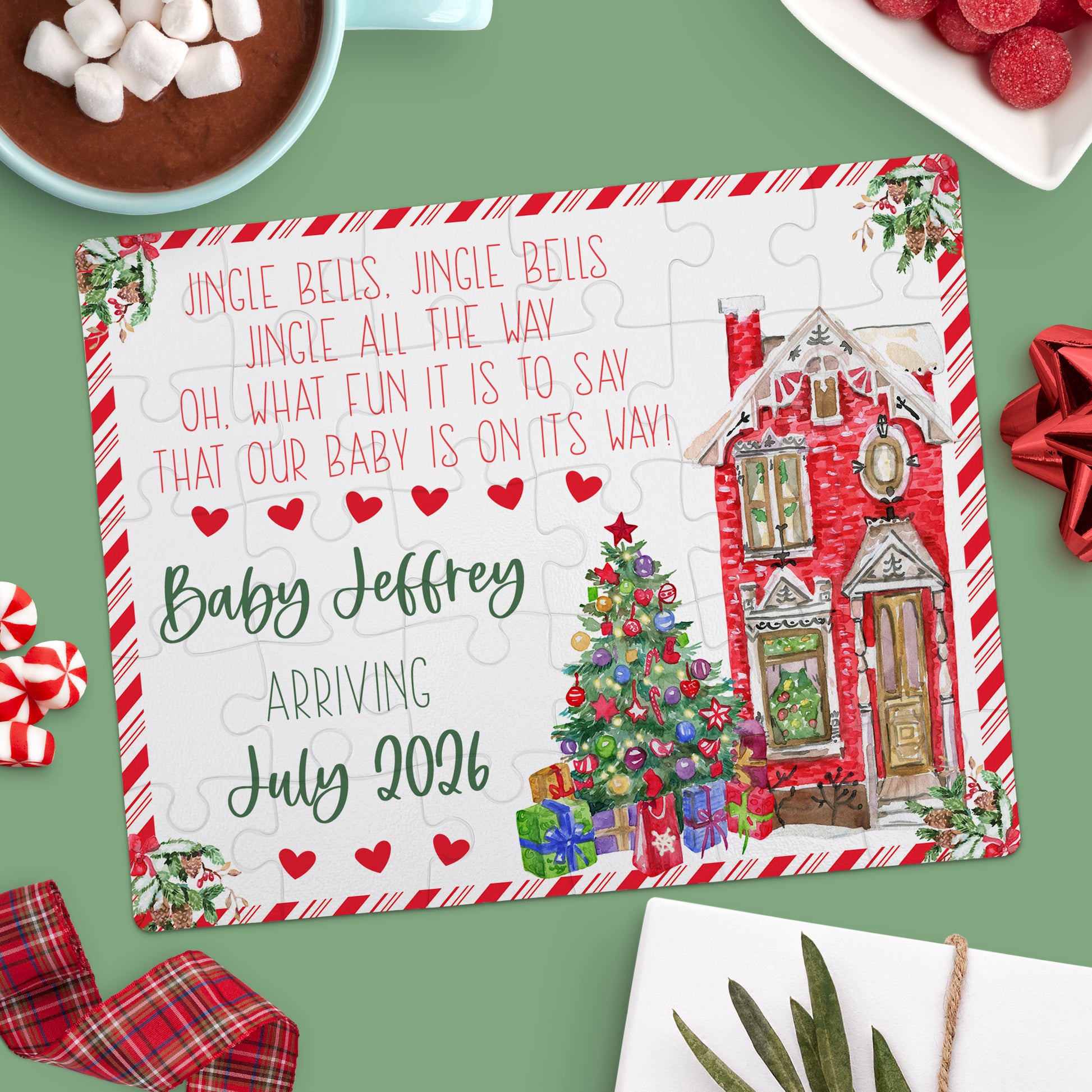A completed holiday-themed jigsaw puzzle on a green table announces "Baby Jeffrey arriving July 2024" next to a Christmas tree and a red house, surrounded by festive treats.